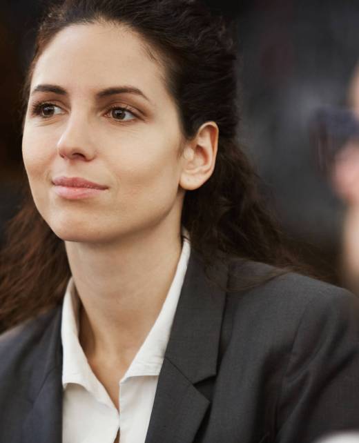 Pretty young brunette businesswoman sitting between colleagues at training, seminar or conference